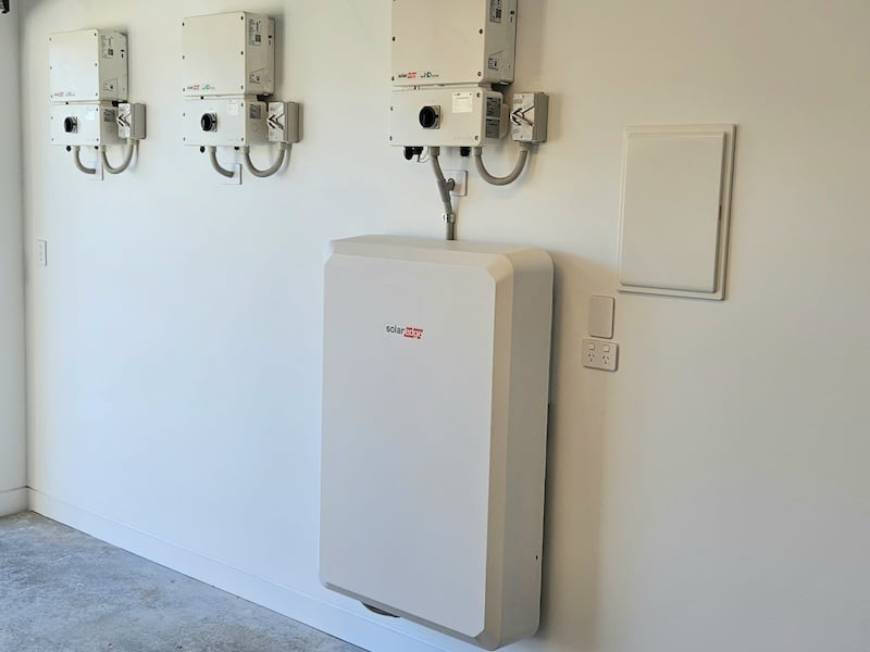 Picture of a client standing and pointing to his battery storage